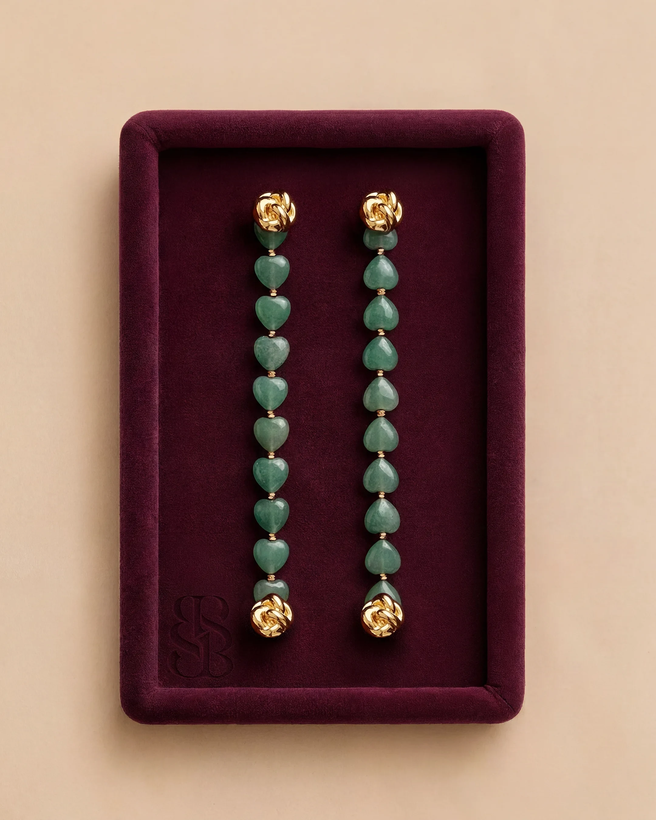 Jade Hearts Signature Strand | Perhiasan batu alam Marylebone Abaya Bint Saeed Abu Dhabi Jade Hearts Signature Strand Bint Saeed untuk Marylebone Abaya — sepasang strand hati jade alam lepas dengan perangkat Knotted Line emas di nampan beludru burgundy. Perhiasan batu alam dapat dipertukarkan untuk garment desainer Bint Saeed. Abaya desainer mewah dengan perhiasan batu alam Bint Saeed Abu Dhabi, UEA — abaya A-line anggun dengan Onyx Strands lepas dan Signature Strands dapat dipertukarkan untuk penggemar fashion, editor fashion, kurator, audiens warisan budaya, diplomat, pembukaan galeri, dan lemari internasional di London, Paris, Riyadh, Doha, dan dunia. Dibuat di Abu Dhabi. Pengiriman dunia. Bint Saeed Abu Dhabi, Uni Emirat Arab.