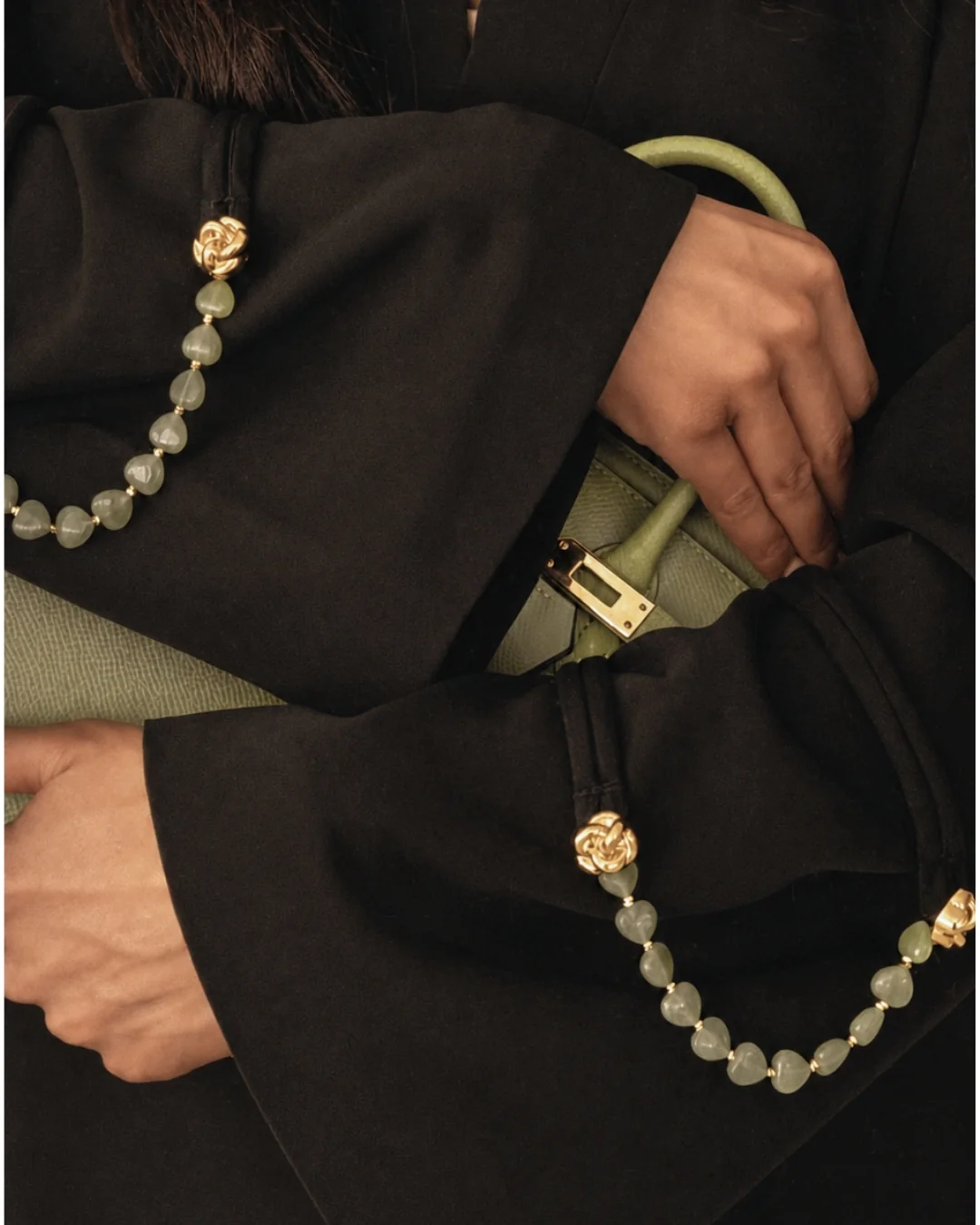 Marylebone Abaya dengan Jade Hearts Strand lifestyle | Perhiasan batu alam Bint Saeed Abu Dhabi Detail lifestyle Bint Saeed Marylebone Abaya dengan Jade Hearts Signature Strand di atas lengan lebar dan tas hijau sage — perhiasan jade alam lepas sebagai aksen lengan dan tas pada abaya desainer dengan batu alam. Abaya desainer mewah dengan perhiasan batu alam Bint Saeed Abu Dhabi, UEA — abaya A-line anggun dengan Onyx Strands lepas dan Signature Strands dapat dipertukarkan untuk penggemar fashion, editor fashion, kurator, audiens warisan budaya, diplomat, pembukaan galeri, dan lemari internasional di London, Paris, Riyadh, Doha, dan dunia. Dibuat di Abu Dhabi. Pengiriman dunia. Bint Saeed Abu Dhabi, Uni Emirat Arab.