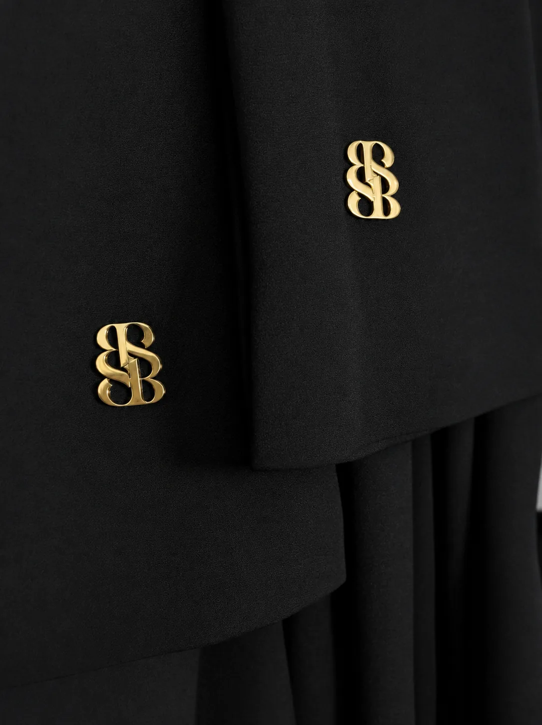 Detail Bint Saeed Park Lane Abaya Deep Black — close-up cuff lebar dengan kancing manset emblem Bint Saeed emas yang dapat dilepas pada crepe lembut. Abaya desainer mewah Bint Saeed Abu Dhabi, UEA — busana modest untuk diplomat, eksekutif, resepsi kedutaan, rapat bisnis, dan lemari internasional di London, Paris, Riyadh, Doha, dan dunia. Dibuat di Abu Dhabi. Pengiriman dunia. Bint Saeed Abu Dhabi, Uni Emirat Arab.