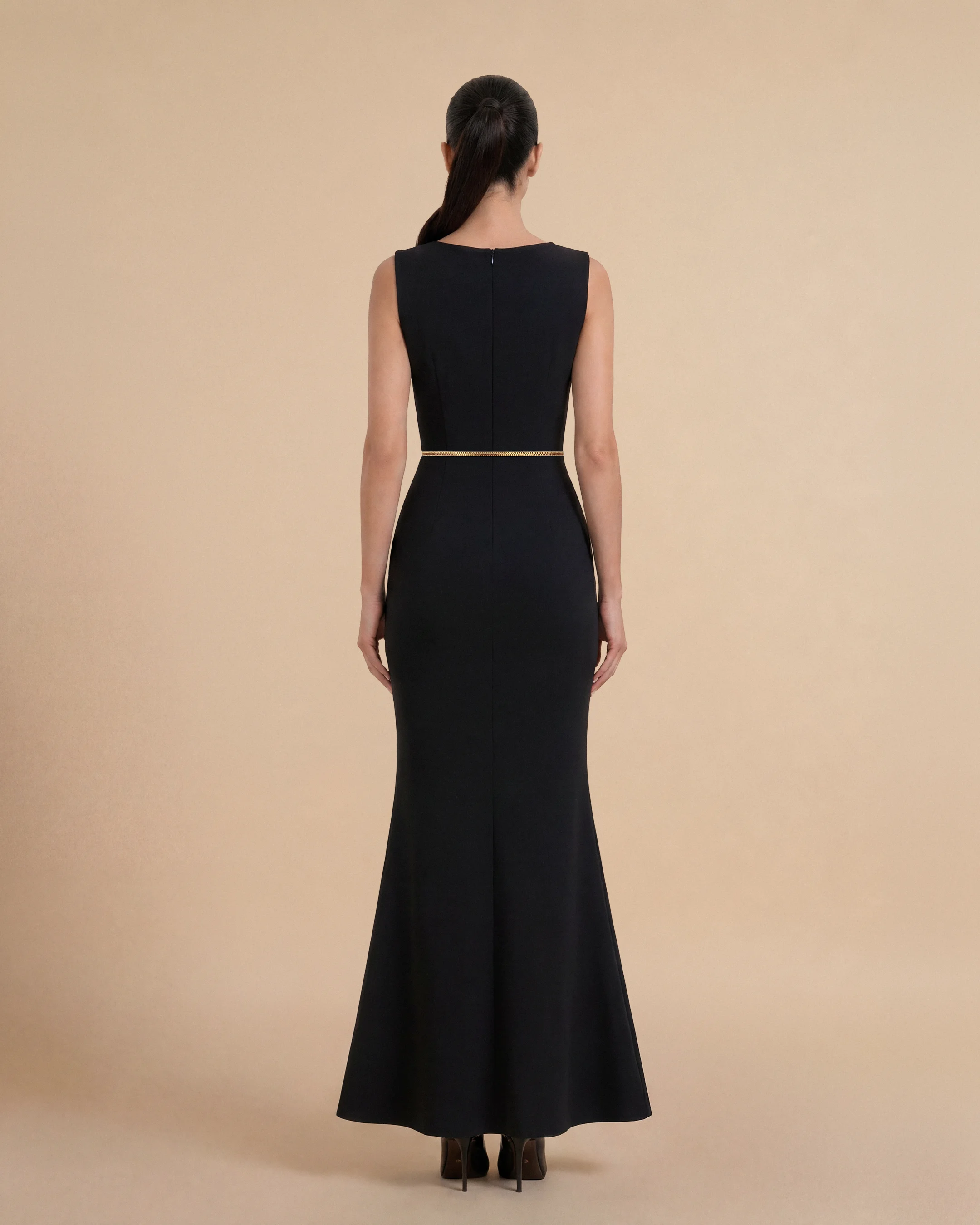Tampak belakang Bint Saeed Hampstead Dress Hitam pekat menonjolkan bahu terstruktur, garis arsitektural bersih, dan panjang maxi mengalir dari tailoring Abu Dhabi yang halus. Gaun maxi krepe premium berlapis penuh dengan garis leher drape elegan, siluet lembut terbentuk, saku sisi tersembunyi, dan trim Al Talli tenun signature di pinggang — warisan Emirati diakui UNESCO, ditafsir ulang di Abu Dhabi. Dipakai sendiri atau di bawah abaya. Dibuat di Abu Dhabi, UEA. Pengiriman dunia. Bint Saeed Abu Dhabi, Uni Emirat Arab.
