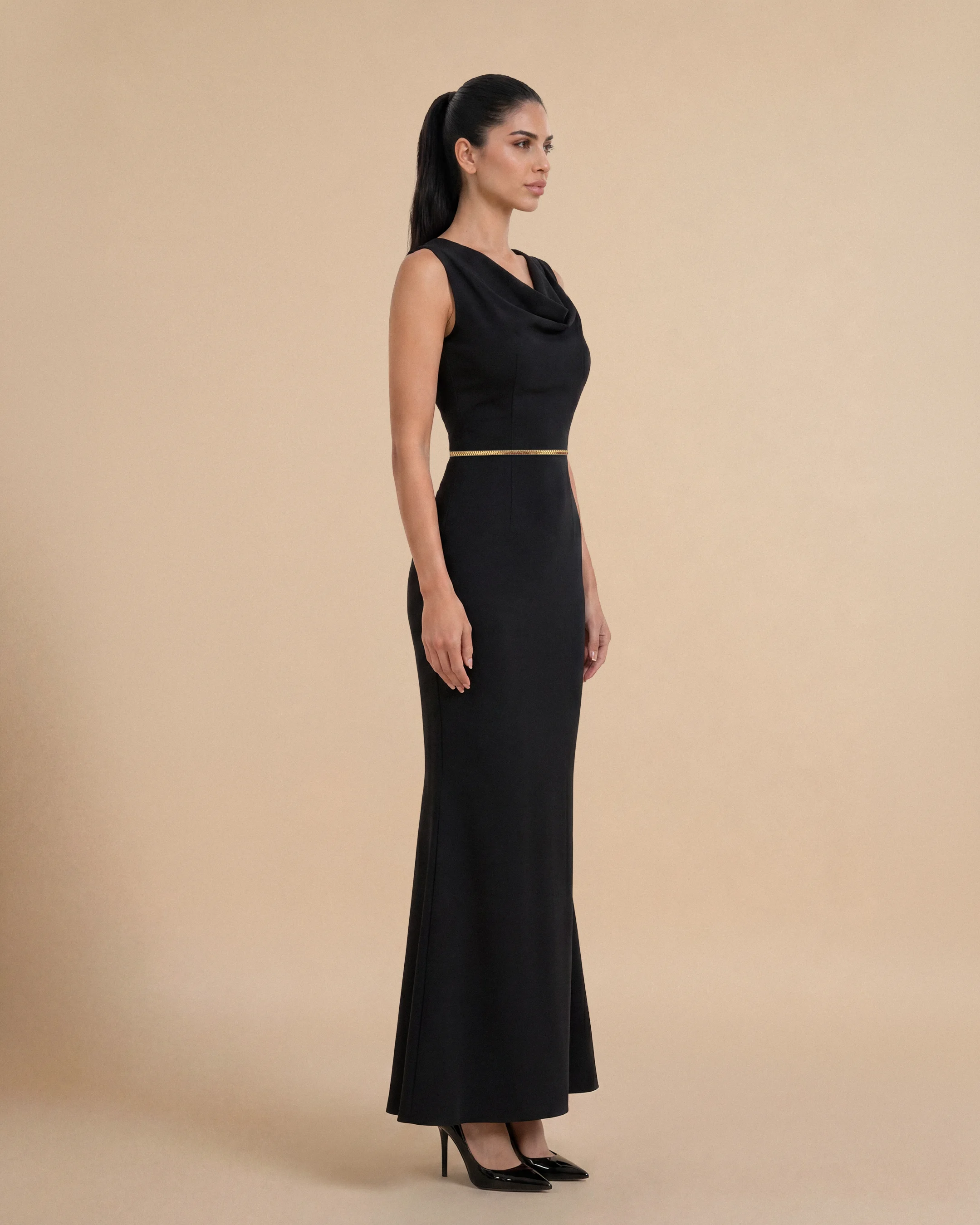 Tampak samping Bint Saeed Hampstead Dress Hitam pekat menampilkan siluet lembut terbentuk, flare ringan, dan gerakan anggun melalui krepe premium. Gaun maxi krepe premium berlapis penuh dengan garis leher drape elegan, siluet lembut terbentuk, saku sisi tersembunyi, dan trim Al Talli tenun signature di pinggang — warisan Emirati diakui UNESCO, ditafsir ulang di Abu Dhabi. Dipakai sendiri atau di bawah abaya. Dibuat di Abu Dhabi, UEA. Pengiriman dunia. Bint Saeed Abu Dhabi, Uni Emirat Arab.