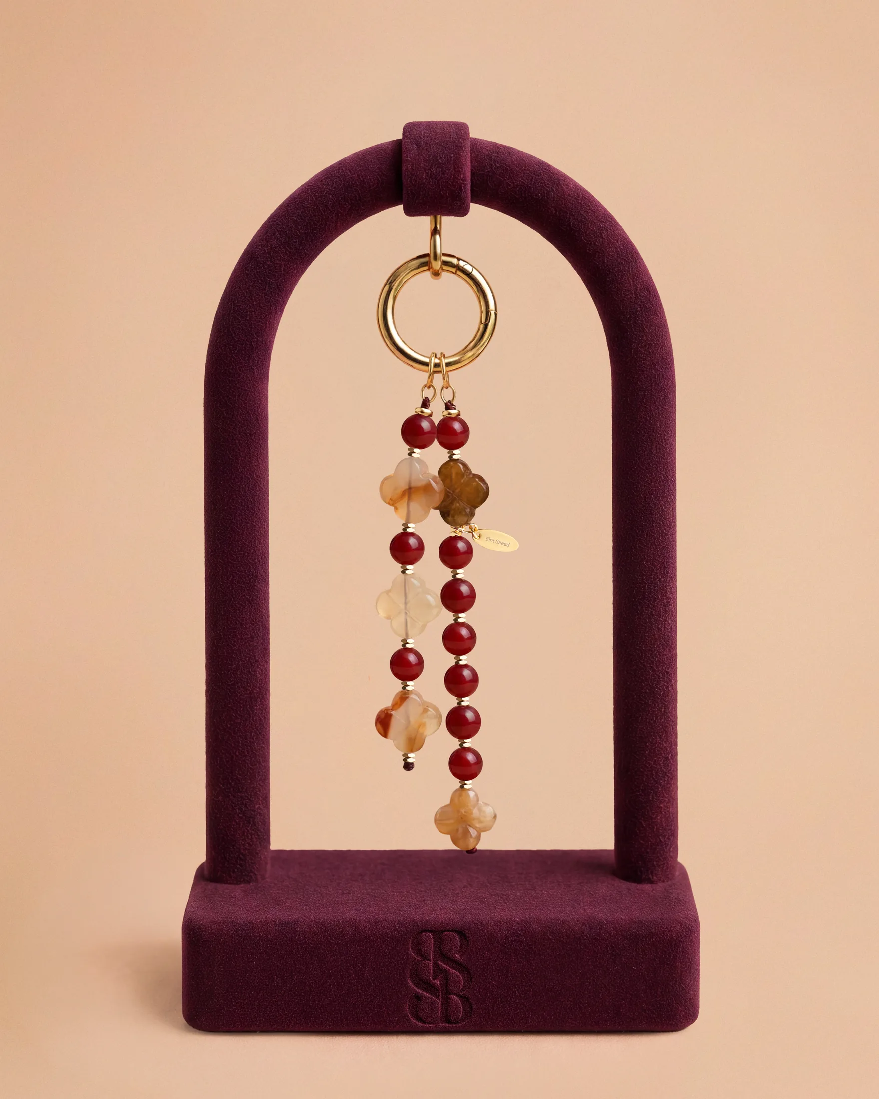 Liontin tas Al Ain Oasis I jade fuchsia — dua untaian menjuntai jade fuchsia dengan Rosette Al Ain ukiran tangan, aksesori tas mewah batu alam Bint Saeed Abu Dhabi. Bint Saeed Abu Dhabi, Uni Emirat Arab.