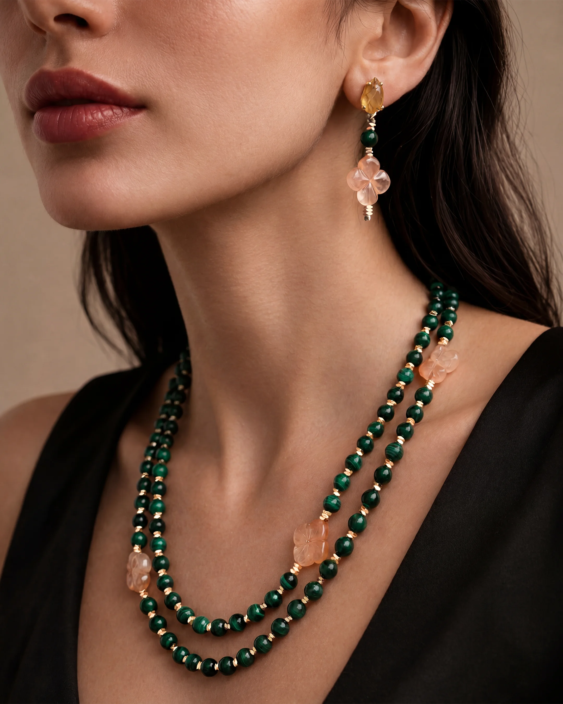 Model wearing the Al Ain Malachite necklace — natural malachite beads with 18K gold-plated signature hardware styled on black, showing length and drape — handcrafted stone necklace Abu Dhabi. Bint Saeed أبوظبي، الإمارات العربية المتحدة.