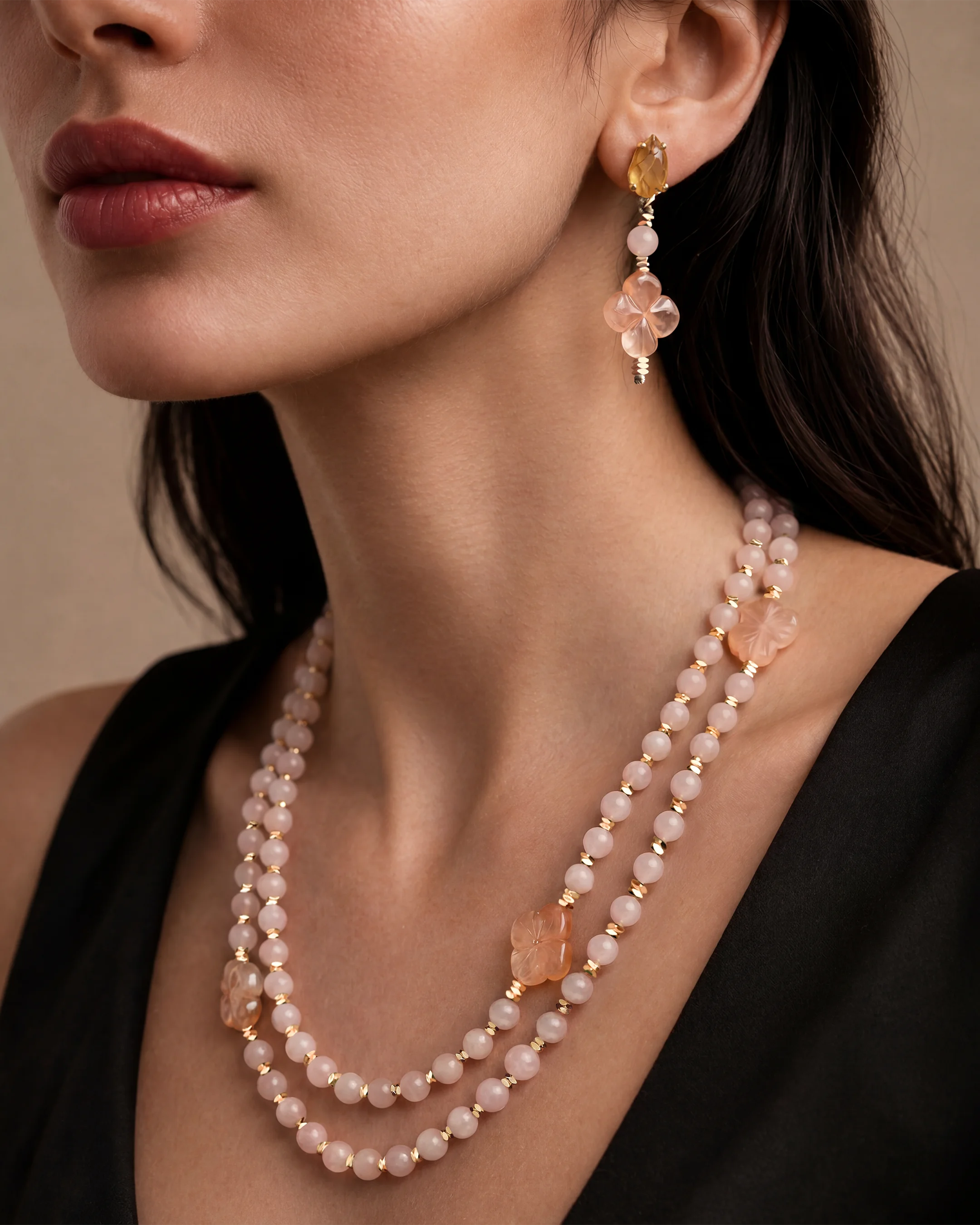 Model wearing the Al Ain Rose Quartz necklace — soft pink hand-knotted rose quartz beads with signature clasp styled on black, showing convertible length — pairs with rose quartz abaya strand. Bint Saeed Abu Dhabi, Vereinigte Arabische Emirate.