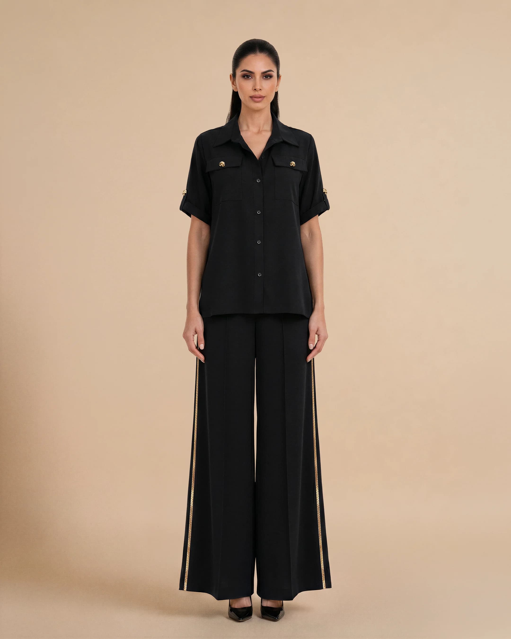 Bint Saeed Soho Set Hitam pekat, tampak depan. Set perjalanan desainer mewah dengan kemeja oversize krepe premium dan celana palazzo kaki lebar, trim Al Talli tradisional Emirati diakui UNESCO di sisi celana dan kancing Knotted Line emas signature. Beli outfit perjalanan elegan UEA — busana modest khaleeji dan ready-to-wear Emirati kontemporer dari Abu Dhabi dan Dubai ke Doha, GCC, London, Paris, Milan, dan dunia. Dibuat di Abu Dhabi, UEA. Pengiriman dunia. Bint Saeed Abu Dhabi, Uni Emirat Arab.