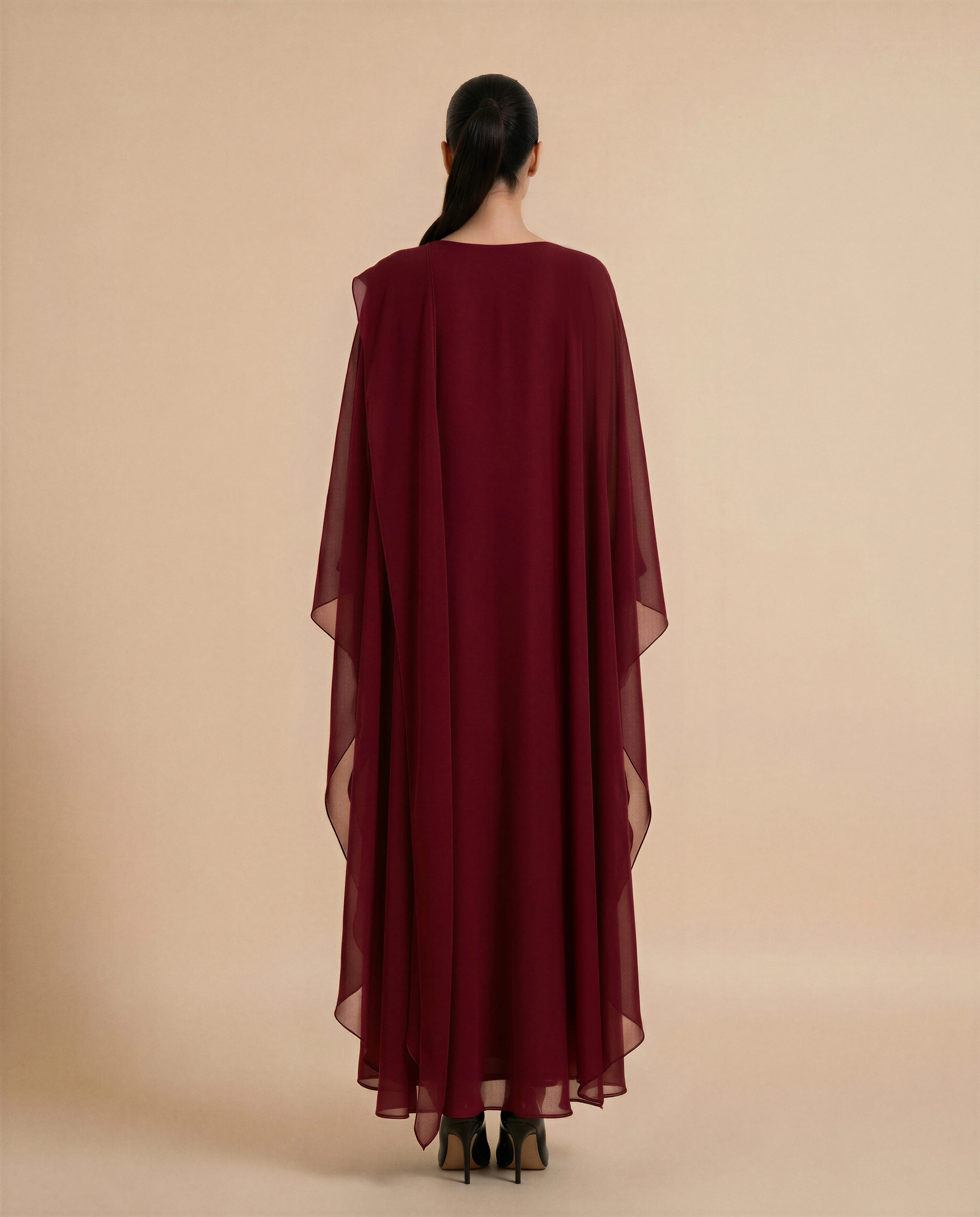 Kaftan Mayfair dalam kain chiffon crepe Merah Marun Gelap, tampak belakang. Kaftan mewah kontemporer dari Bint Saeed Abu Dhabi, Uni Emirat Arab, menonjolkan gerakan anggun, chiffon berlapis ringan, dan desain busana malam yang elegan.