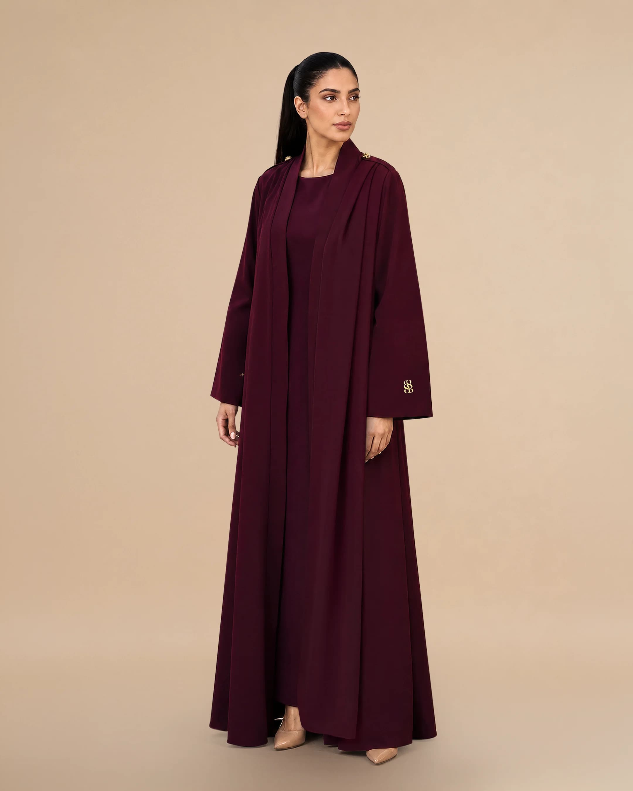 Pandangan tiga suku Bint Saeed Park Lane Abaya Dark Maroon mempamerkan jatuhan A-line anggun, pergerakan skarf bahu bersepadu, bahu berstruktur dengan butang Knotted Line, dan siluet crepe terjahit. Abaya pereka mewah Bint Saeed Abu Dhabi, UAE — fesyen sopan untuk diplomat, eksekutif, majlis kedutaan, mesyuarat perniagaan, dan almari antarabangsa di London, Paris, Riyadh, Doha, dan seluruh dunia. Dihasilkan di Abu Dhabi. Penghantaran seluruh dunia. Bint Saeed Abu Dhabi, Emiriah Arab Bersatu.