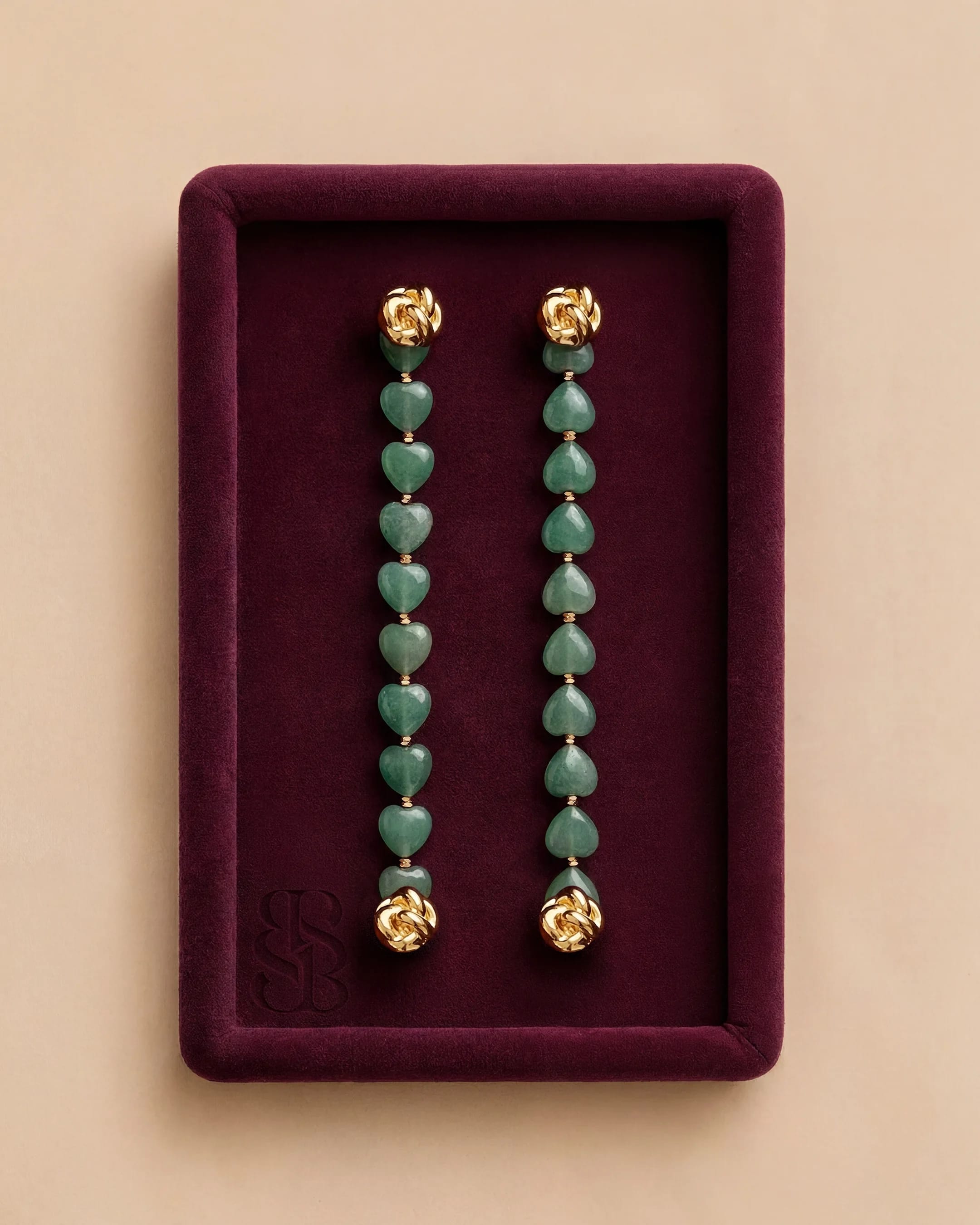 Jade Hearts Signature Strand | Perhiasan batu alam Marylebone Abaya Bint Saeed Abu Dhabi Jade Hearts Signature Strand Bint Saeed untuk Marylebone Abaya — sepasang strand hati jade alam lepas dengan perangkat Knotted Line emas di nampan beludru burgundy. Perhiasan batu alam dapat dipertukarkan untuk garment desainer Bint Saeed. Abaya desainer mewah dengan perhiasan batu alam Bint Saeed Abu Dhabi, UEA — abaya A-line anggun dengan Onyx Strands lepas dan Signature Strands dapat dipertukarkan untuk penggemar fashion, editor fashion, kurator, audiens warisan budaya, diplomat, pembukaan galeri, dan lemari internasional di London, Paris, Riyadh, Doha, dan dunia. Dibuat di Abu Dhabi. Pengiriman dunia. Bint Saeed Abu Dhabi, Uni Emirat Arab.