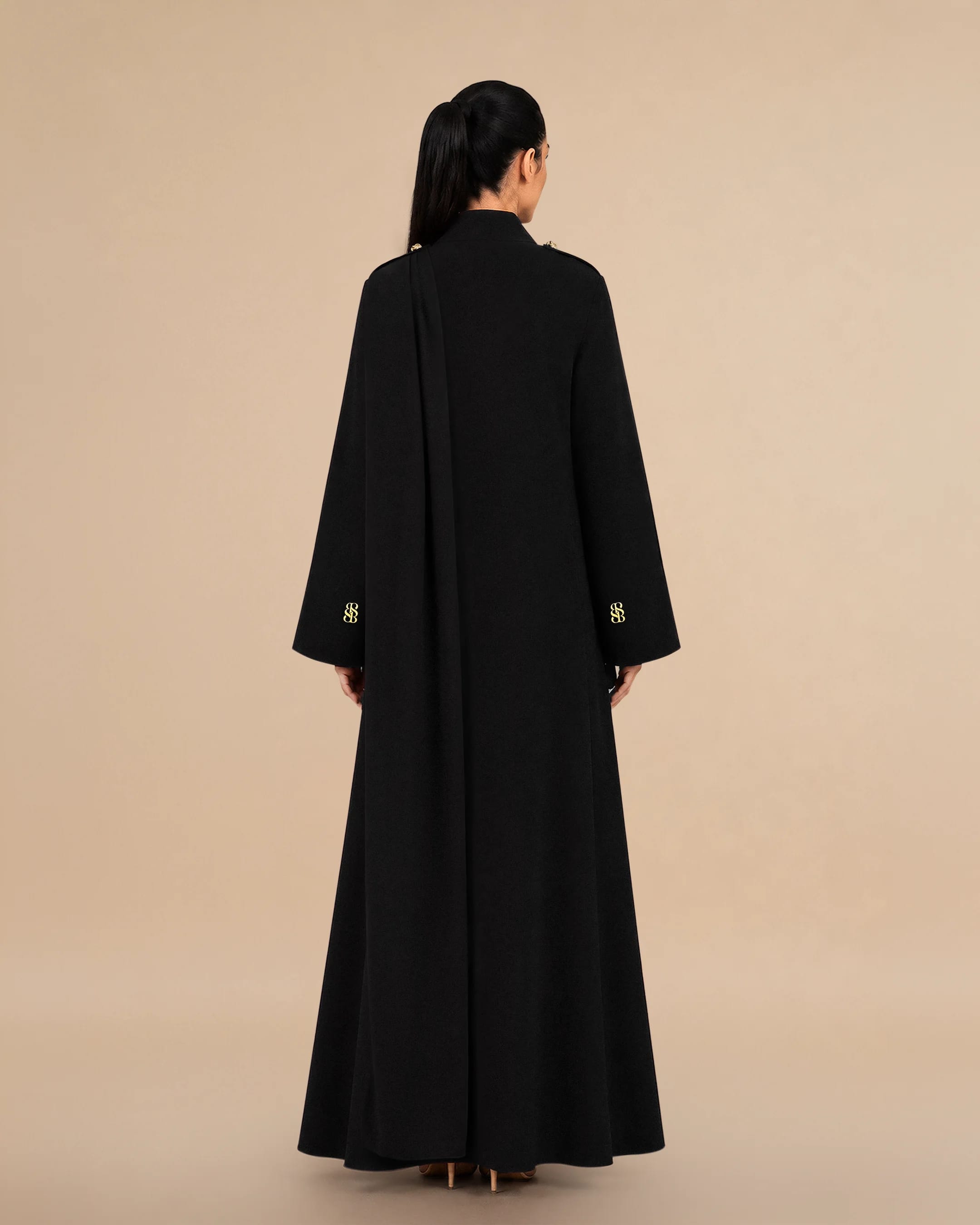 Tampak belakang Bint Saeed Park Lane Abaya Deep Black menonjolkan siluet A-line elegan, drape mengalir penuh, scarf bahu terintegrasi, dan tailoring arsitektural bersih. Abaya desainer mewah Bint Saeed Abu Dhabi, UEA — busana modest untuk diplomat, eksekutif, resepsi kedutaan, rapat bisnis, dan lemari internasional di London, Paris, Riyadh, Doha, dan dunia. Dibuat di Abu Dhabi. Pengiriman dunia. Bint Saeed Abu Dhabi, Uni Emirat Arab.