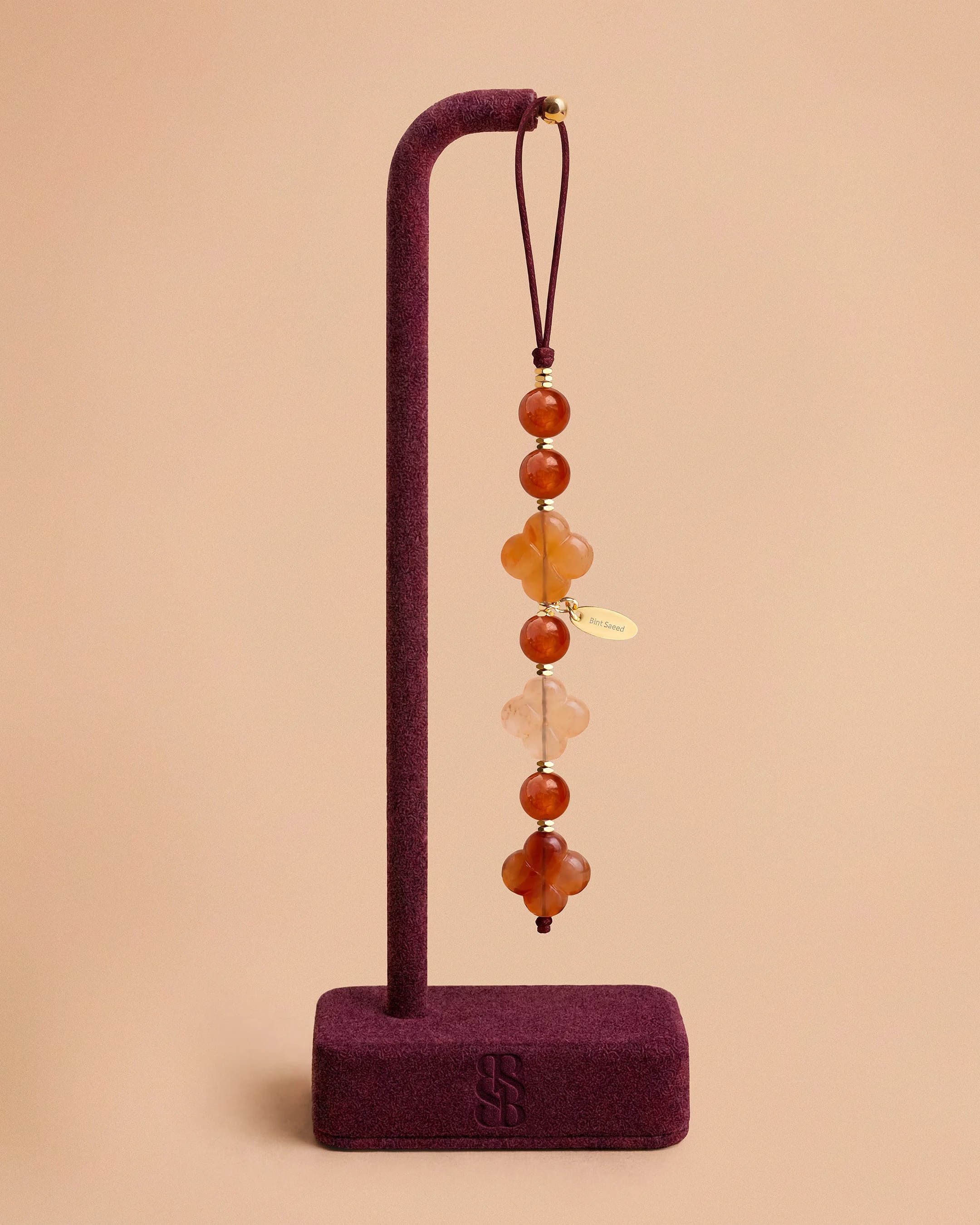 Ciondolo telefono Al Quaa giada arancio in pietra naturale di Bint Saeed: perle di giada arancio calda luminosa, Rosetta di Al Ain in corniola intagliata e ematite sfaccettata placcata oro. Gioiello telefono di lusso artigianale per amanti di pietre naturali e collezioniste di accessori raffinati. Realizzato ad Abu Dhabi, Emirati Arabi Uniti. Spedizione mondiale. Bint Saeed Abu Dhabi, Emirati Arabi Uniti.
