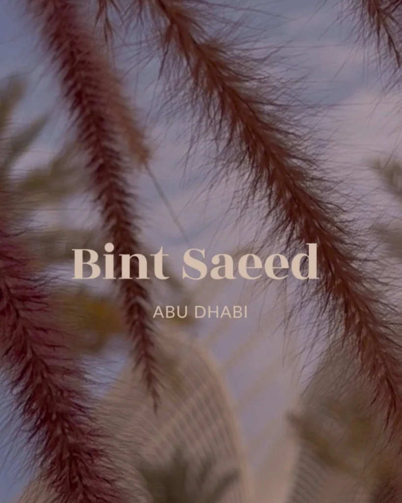 Bint Saeed Abu Dhabi — branded editorial portrait with fountain grass, palms, and contemporary architecture at dusk