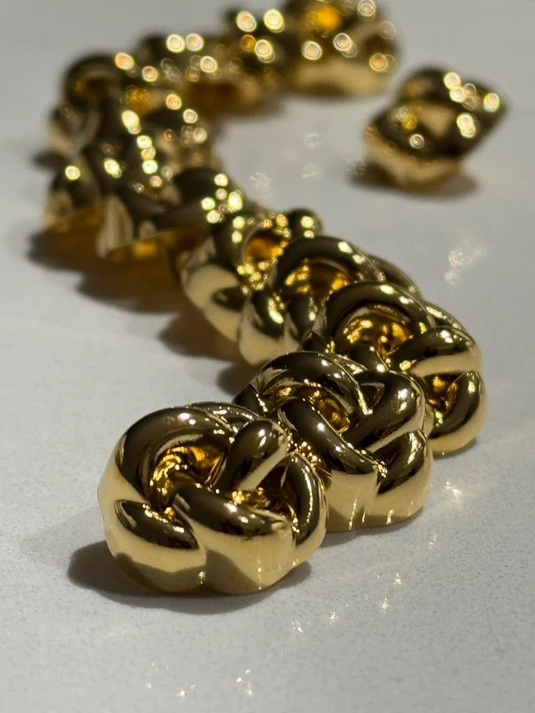 Polished gold knotted chain links — atelier jewellery craftsmanship detail. Bint Saeed Abu Dhabi, United Arab Emirates.