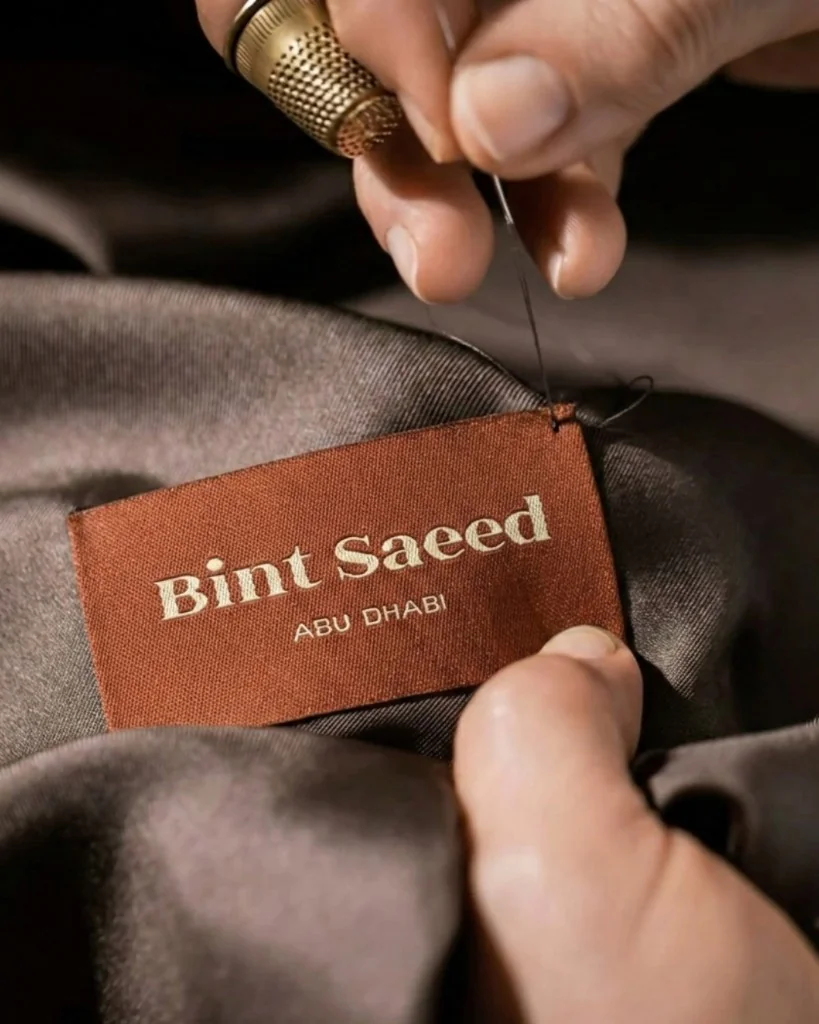 Hand sewing a Bint Saeed Abu Dhabi woven label into a luxury garment. Bint Saeed Abu Dhabi, United Arab Emirates.