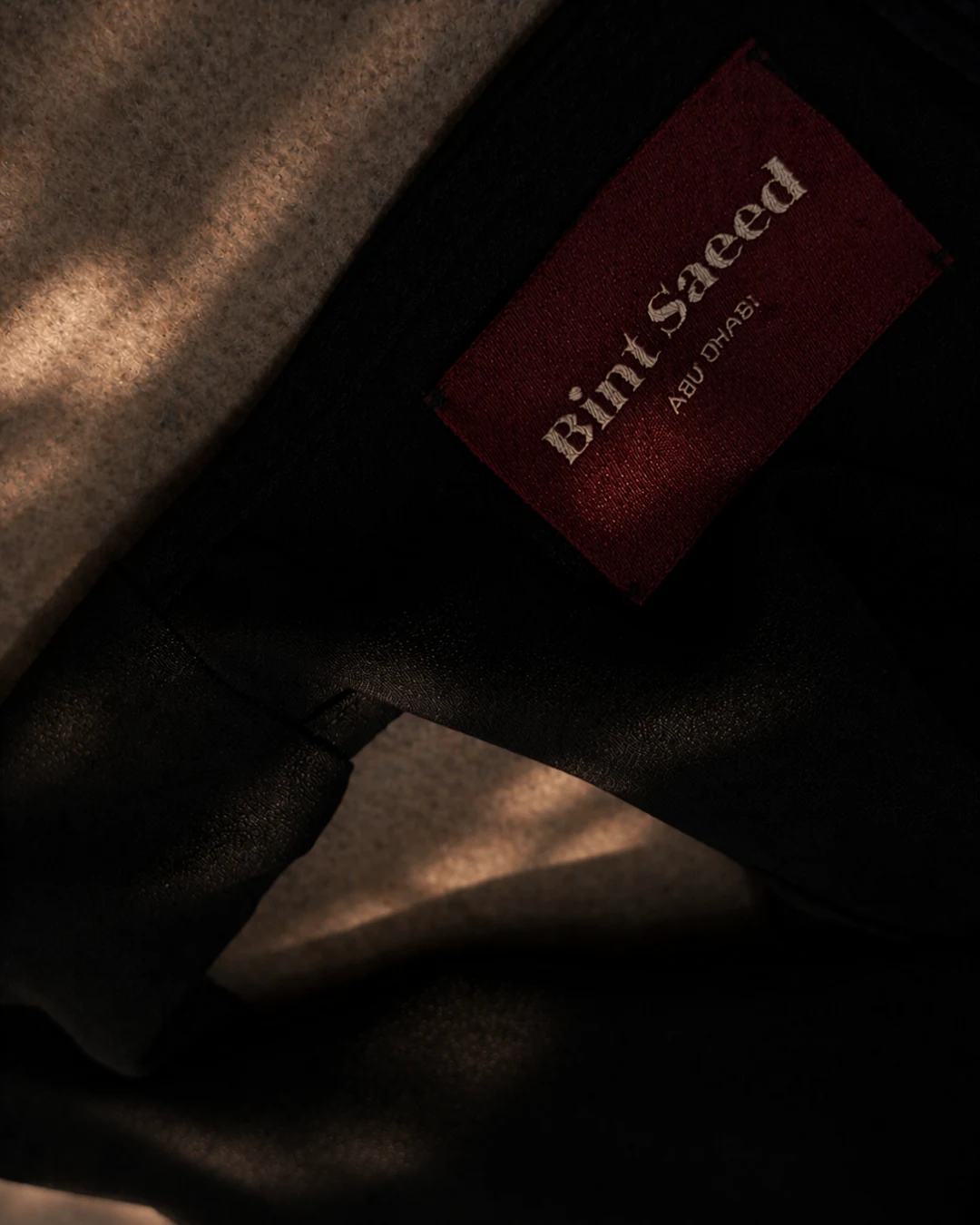 Bint Saeed woven brand label Abu Dhabi on black Hampstead dress interior. Bint Saeed Abu Dhabi, United Arab Emirates.